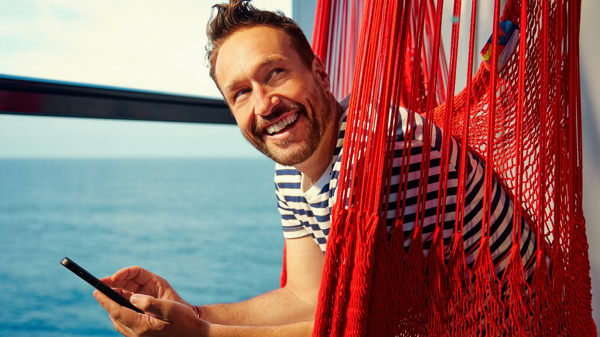 Guest browsing on their phone in a ship-side hammock